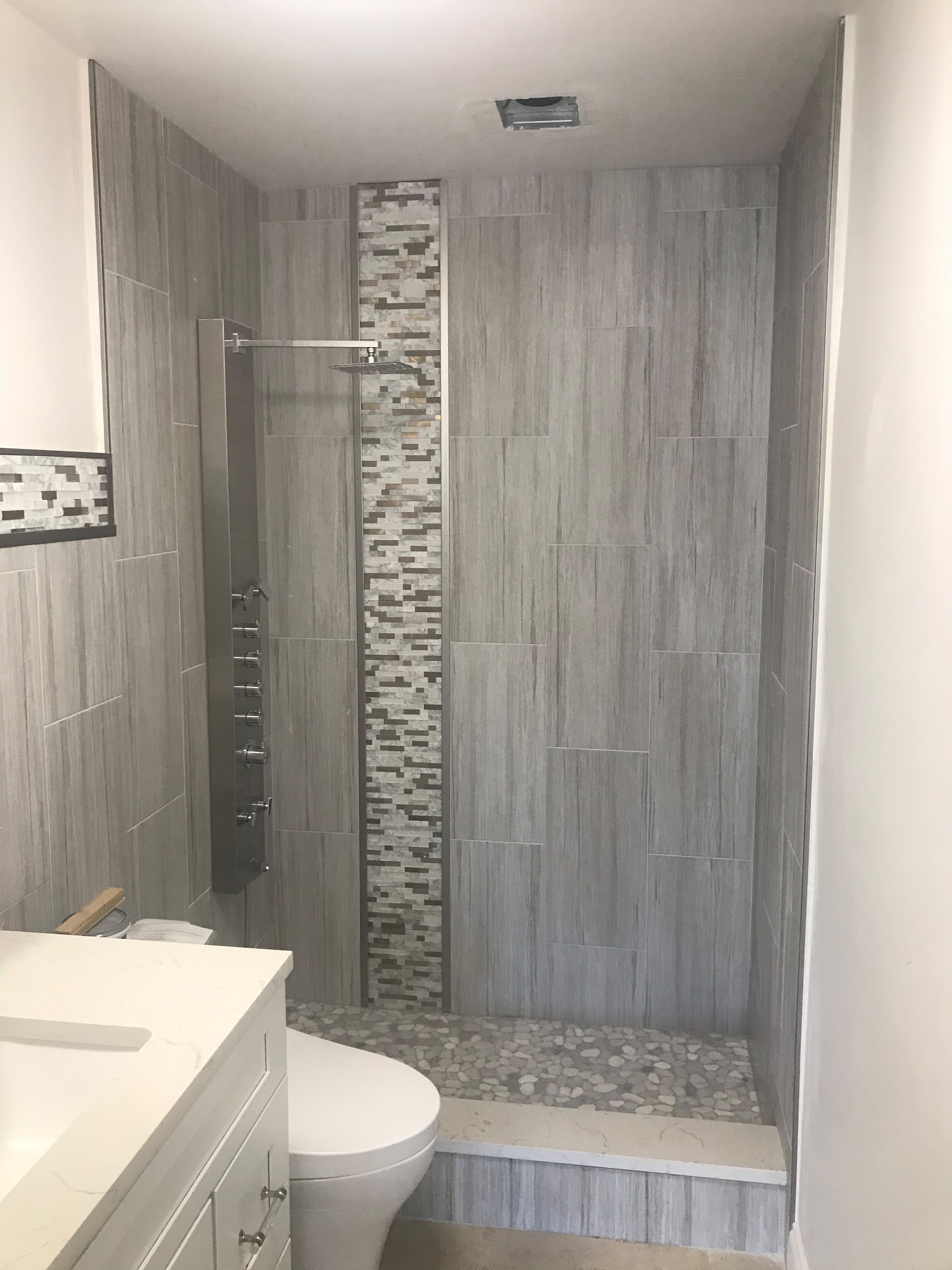 Gray tile shower with mosaic feature strip