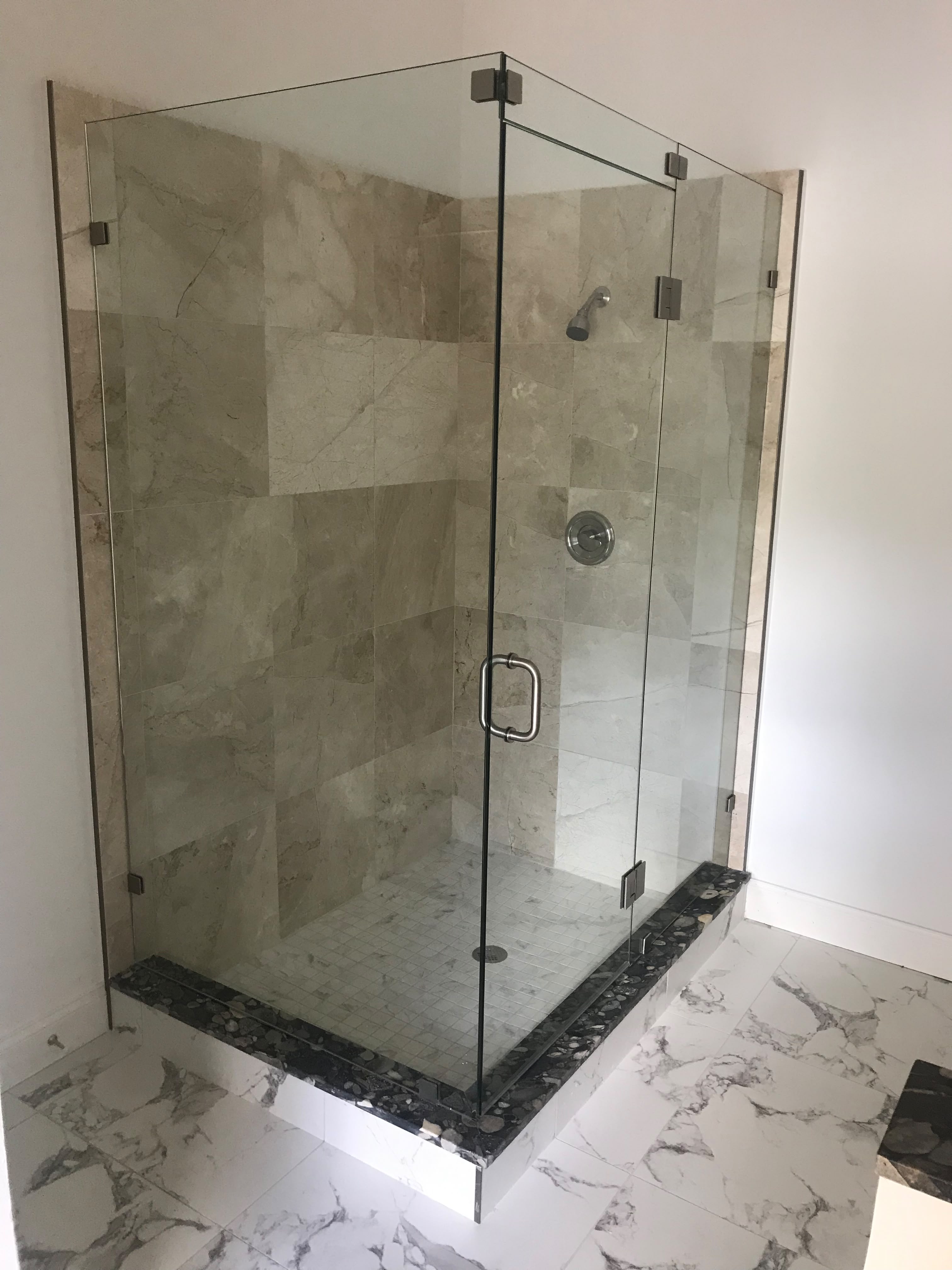 Frameless shower enclosure with stone tile